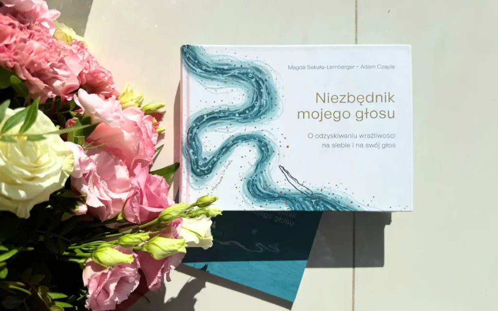 książka "niezbędnik mojego głosu", obok bukiet kwiatów